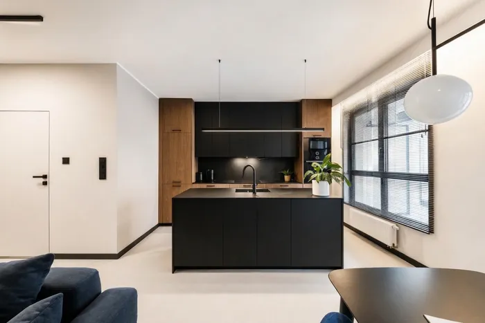 The same apartment without the zigzag light, with a slim black linear pendant on two cables over the kitchen island